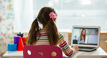 A girl in front of the laptop taking part in an online class.