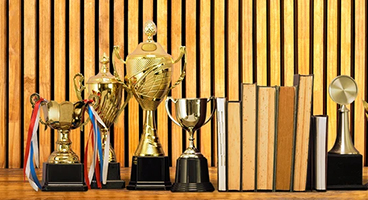 Various trophies stand in front of a wooden wall