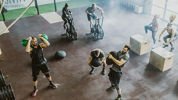 Mehrere Personen treiben Sport in einem Fitnessraum.