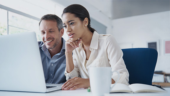 Man and woman in office looking at a laptop to