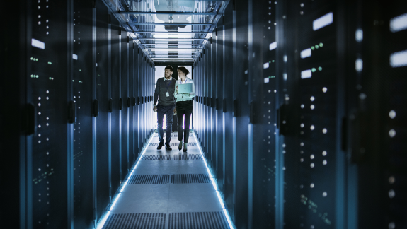 Two people in a corridor with servers in a data center