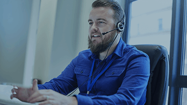 Bearded young man talking on the phone with headset in the office.