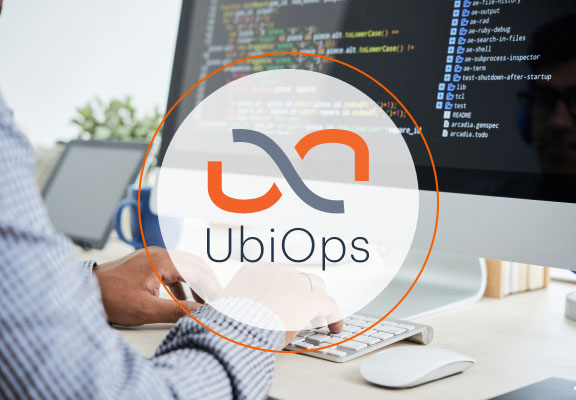 UbiOps Logo vor einem Hintergrund wo jemand Programmiersprache schreibt.