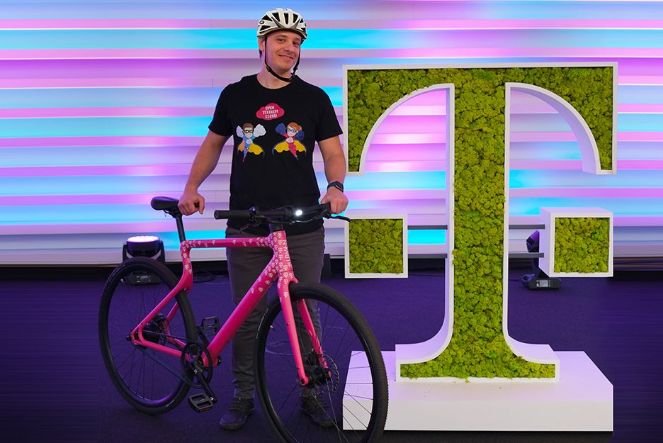 German Santini with bicycle next to planted horizontal T of Telekom