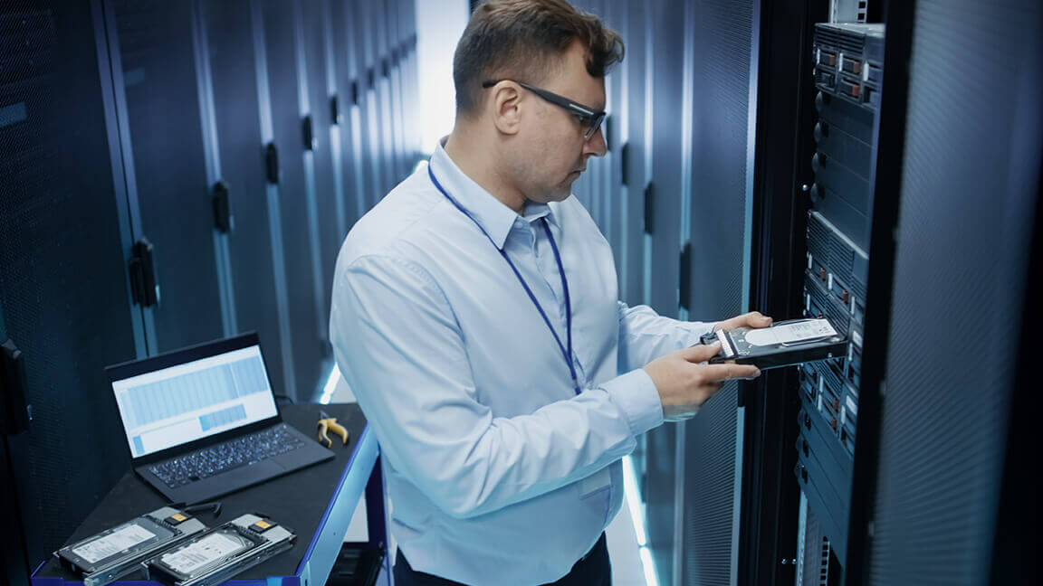 IT specialist checking and replacing modules in a serverroom.